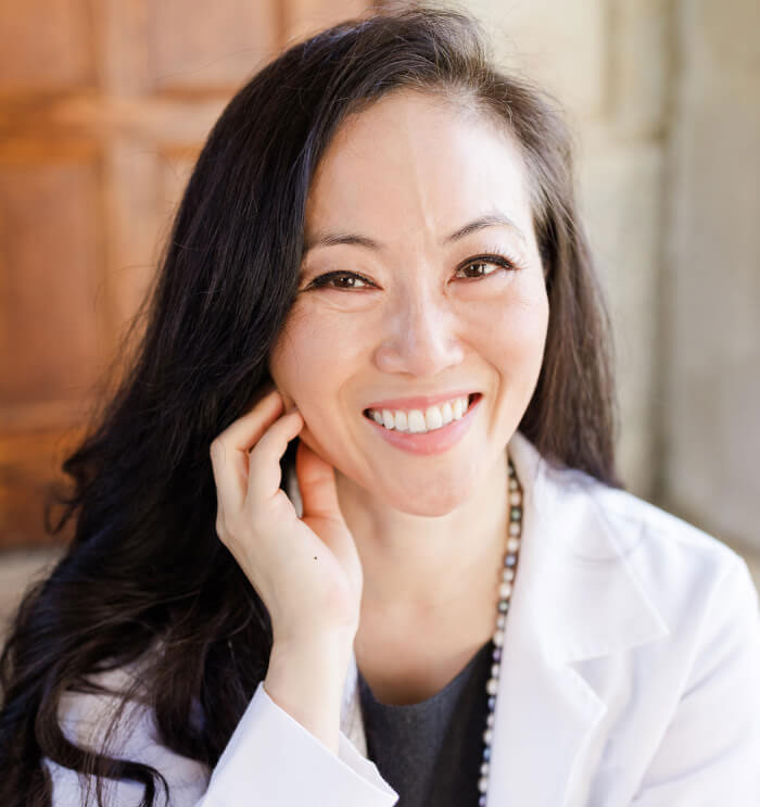 In a white coat, Dr. Christina H. Choe smiles reflecting her friendly and professional character.