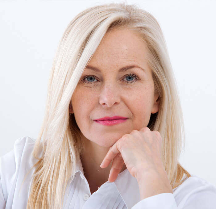 Blonde-haired woman in a white shirt, exuding confidence and warmth in a casual setting