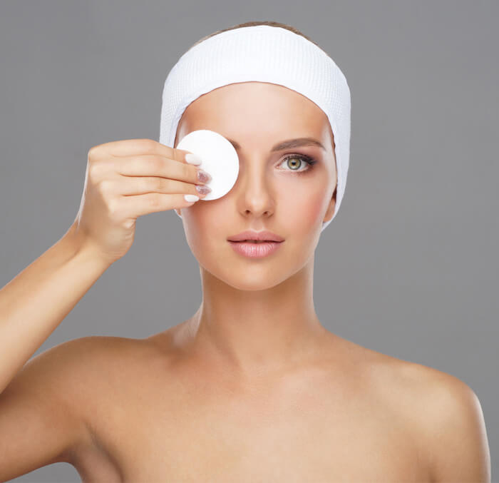 A beautiful woman with a white band draped over her head and holding a white mask before her right eye, exuding elegance and tranquility