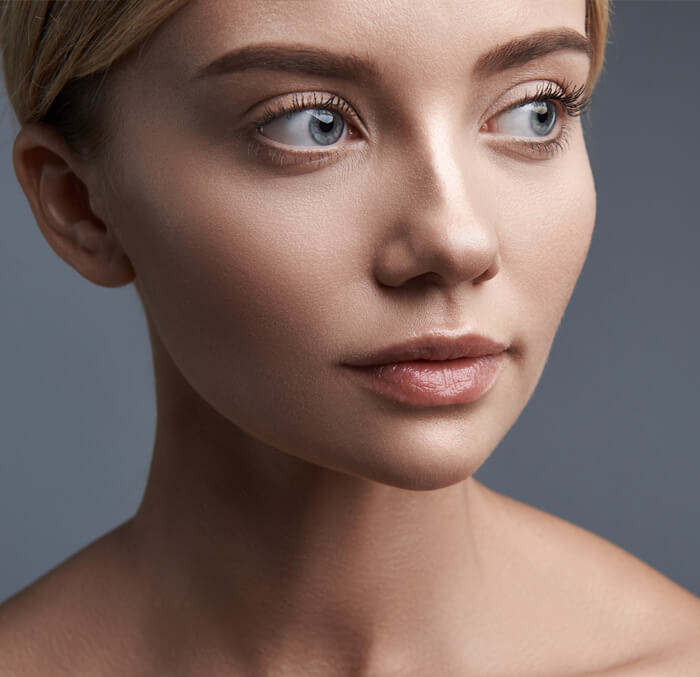 A woman with blonde hair and blue eyes, smiling softly against a neutral background