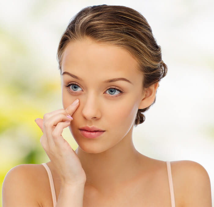 A woman with blue eyes gently holds her hand to her face, conveying a sense of contemplation or emotion